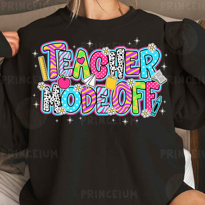 a woman wearing a black teacher sweatshirt with colorful lettering