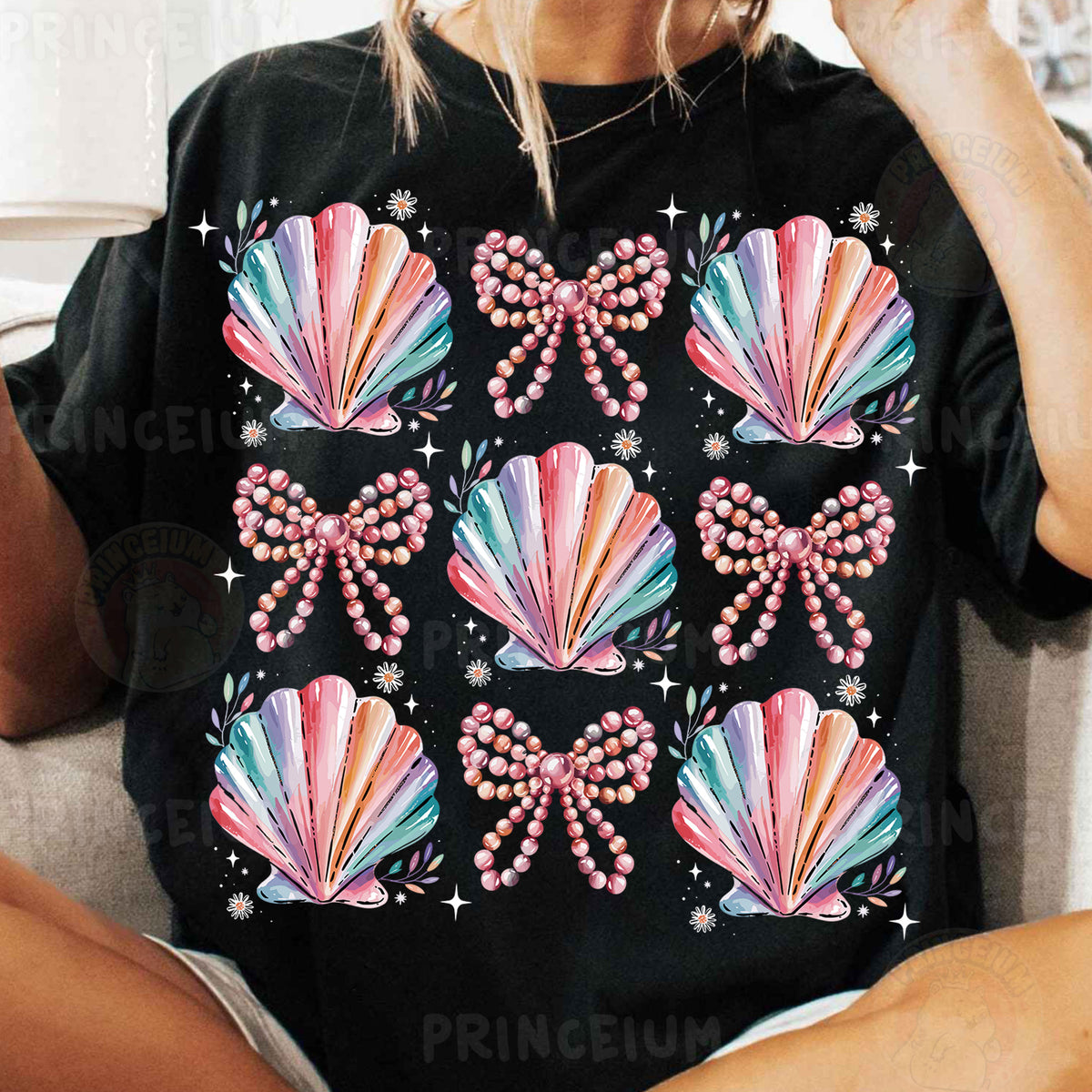 a woman sitting on a couch wearing a black shirt with pink bows and pearls