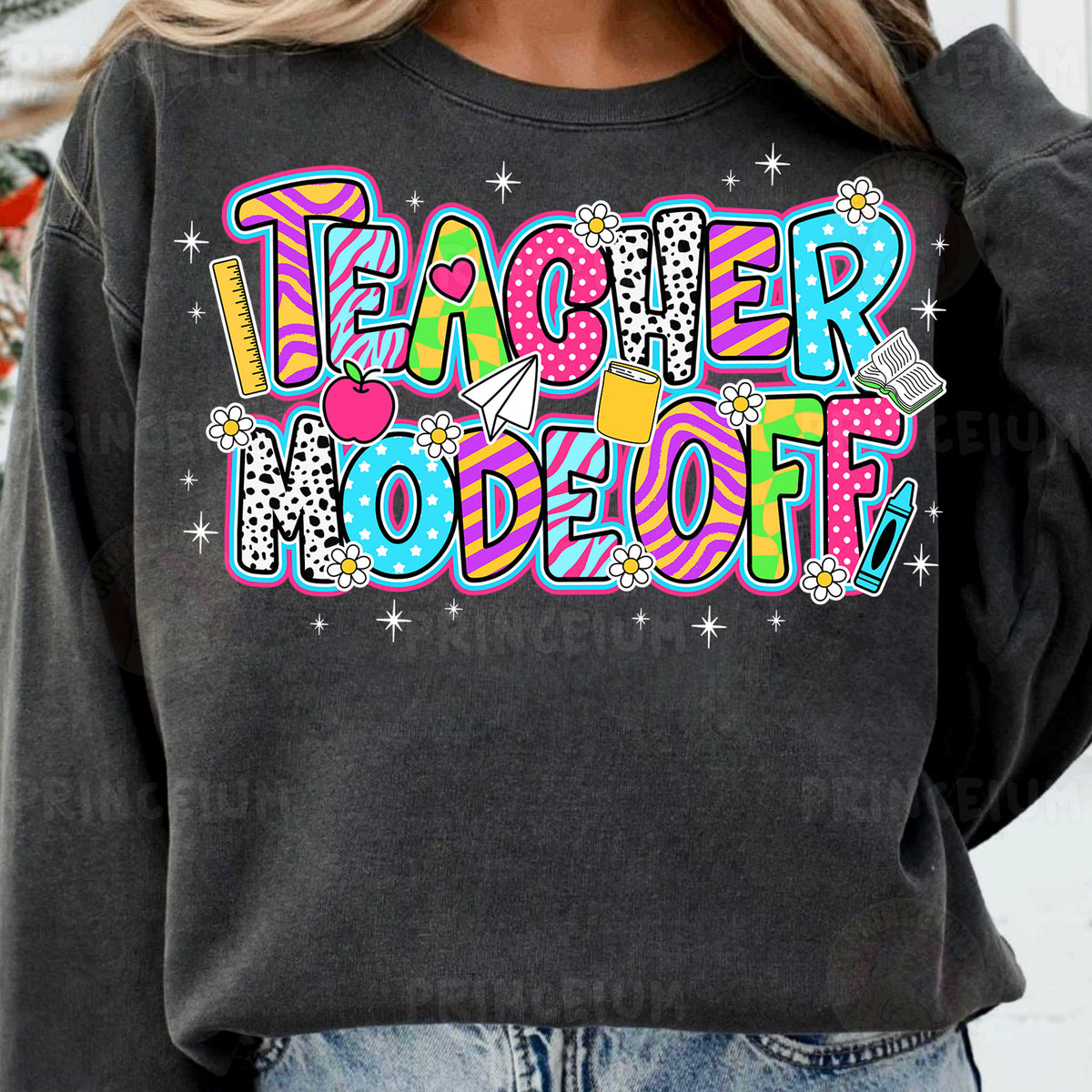 a woman wearing a black teacher sweatshirt with colorful lettering