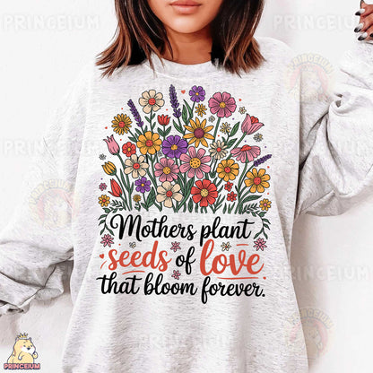 a woman wearing a sweatshirt that says mothers plant seeds of love that bloom forever