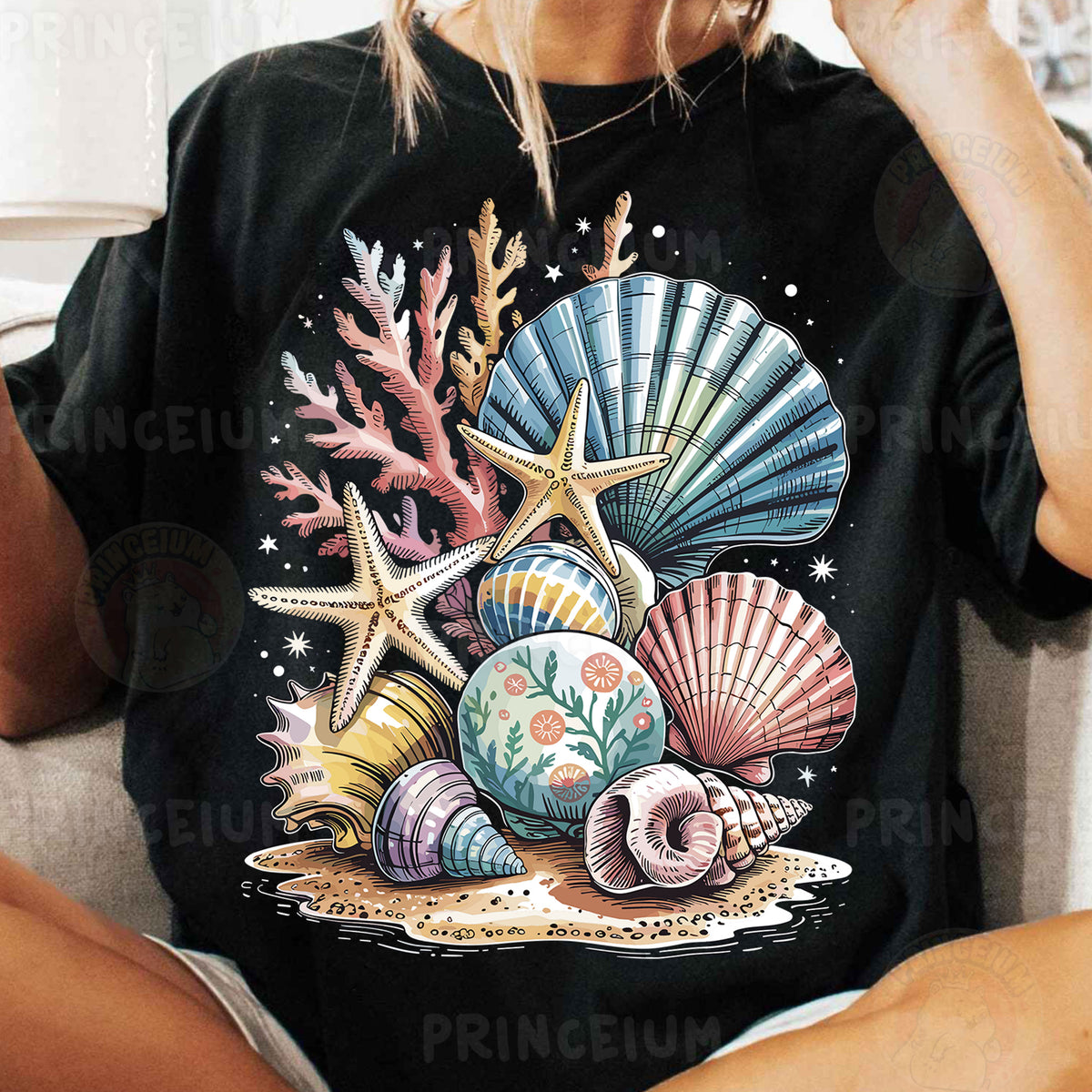 a woman sitting on a couch wearing a black shirt with seashells and star