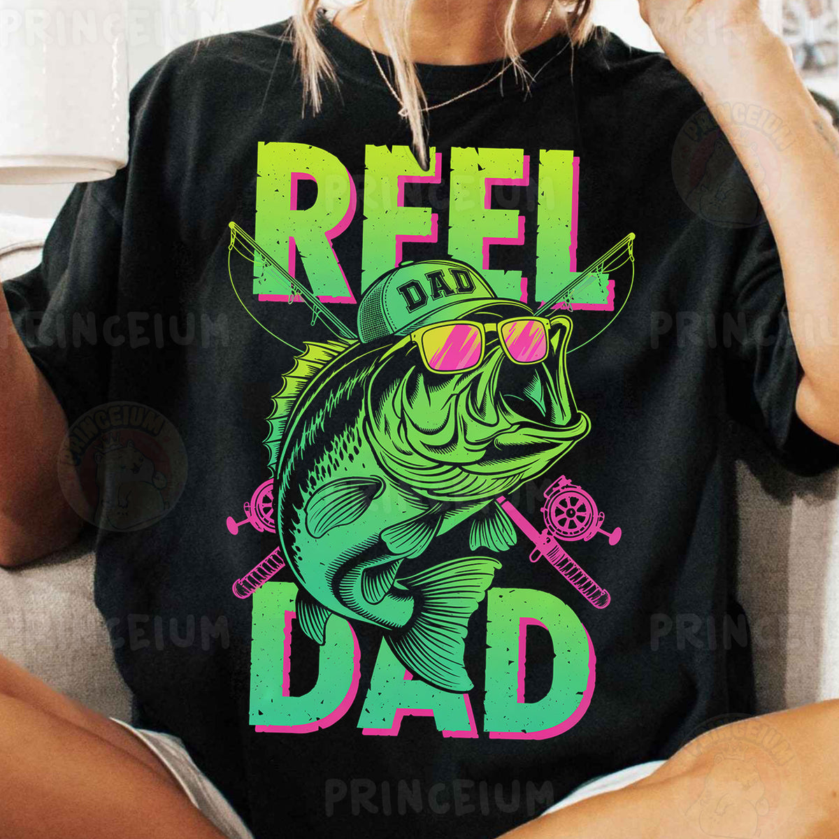 a woman sitting on a couch wearing a t - shirt that says reel dad