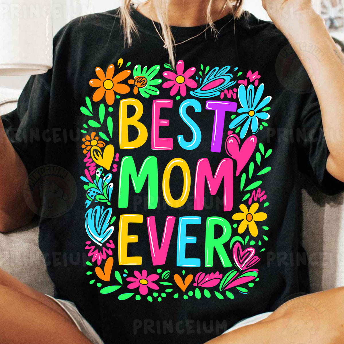 a woman sitting on a couch wearing a t - shirt that says best mom ever