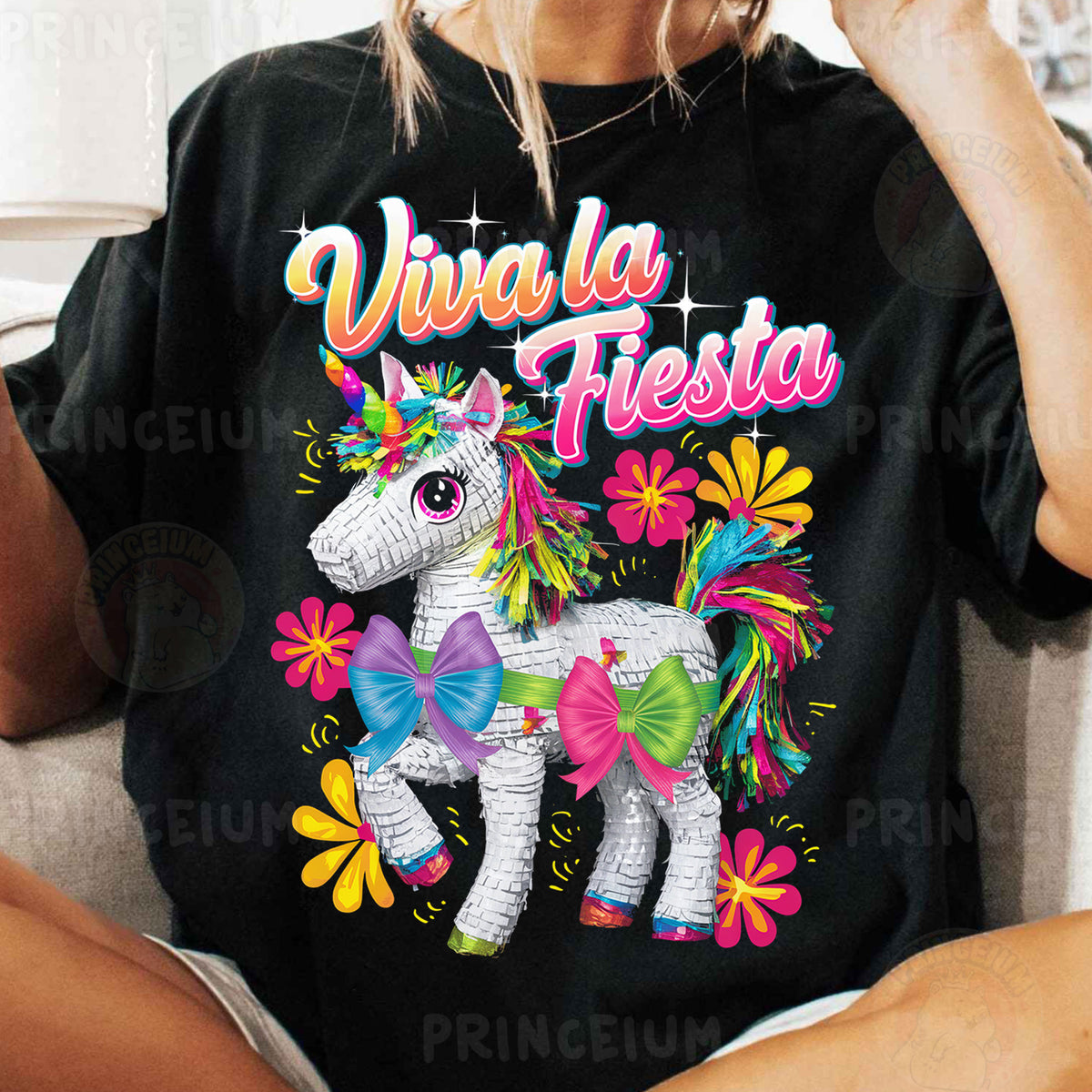a woman sitting on a couch wearing a black shirt with a unicorn on it