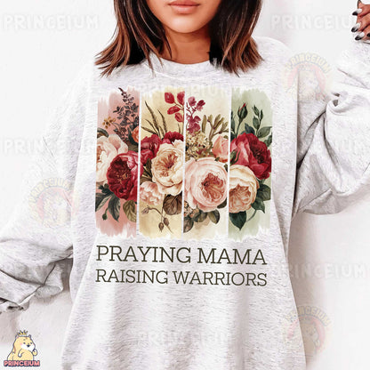 a woman wearing a sweatshirt that says praying mama raising warriors
