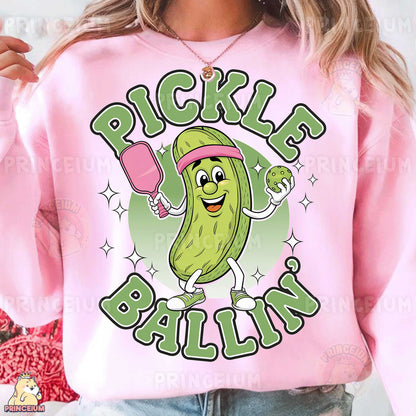 a woman wearing a pink pickle ball sweatshirt