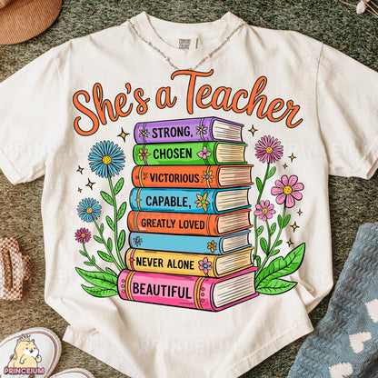 a t - shirt that says she's a teacher with a stack of books