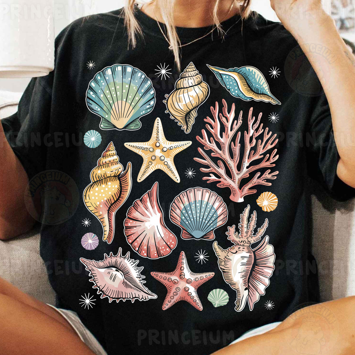 a woman sitting on a couch wearing a black shirt with sea shells and starfish