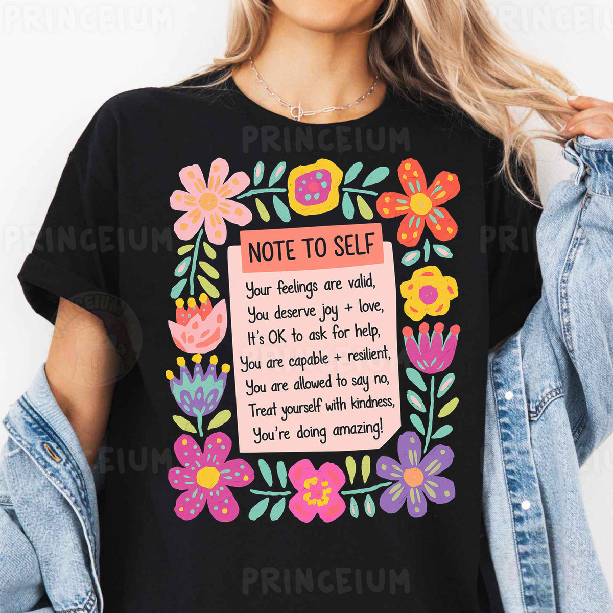 a woman wearing a black t - shirt with colorful flowers and a note to self