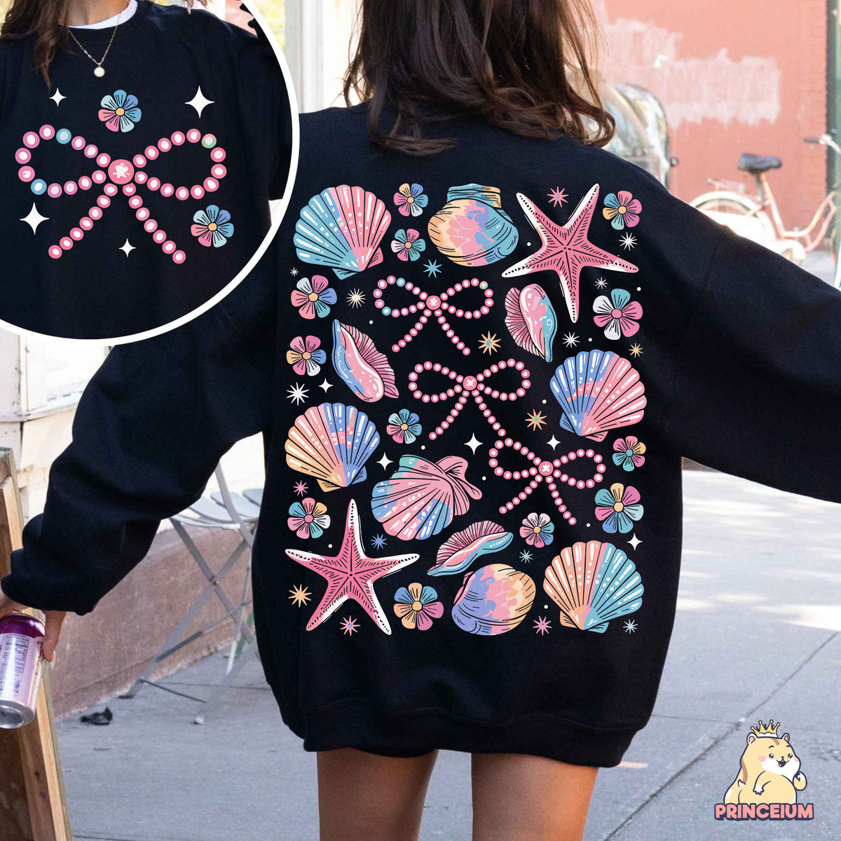 a woman wearing a black sweatshirt with pink and blue seashells on it