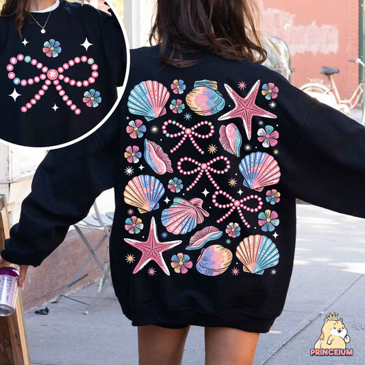 a woman wearing a black sweatshirt with pink and blue seashells on it