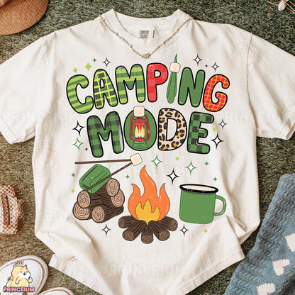 a t - shirt that says camping mode next to a pair of shoes