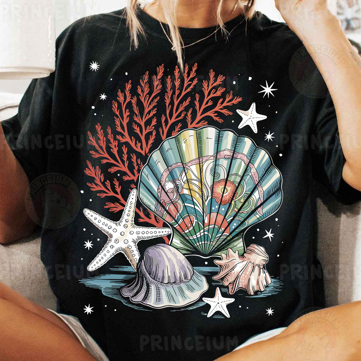 a woman sitting on a couch wearing a black shirt with a seashell and star