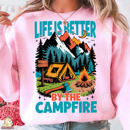 a woman wearing a pink sweatshirt that says life is better by the campfire