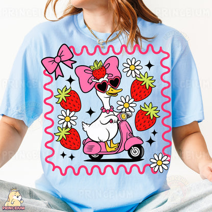 a woman wearing a t - shirt with a duck riding a scooter