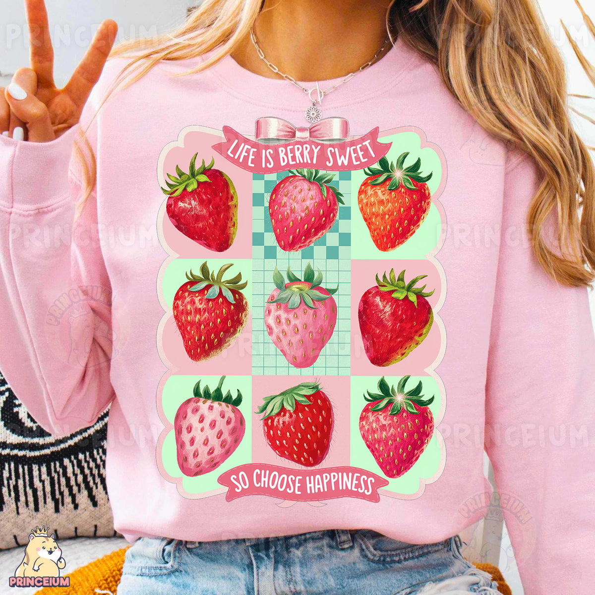 a woman wearing a pink sweatshirt with a graphic of strawberries on it