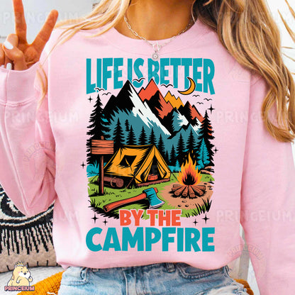 a woman wearing a pink shirt that says life is better by the campfire